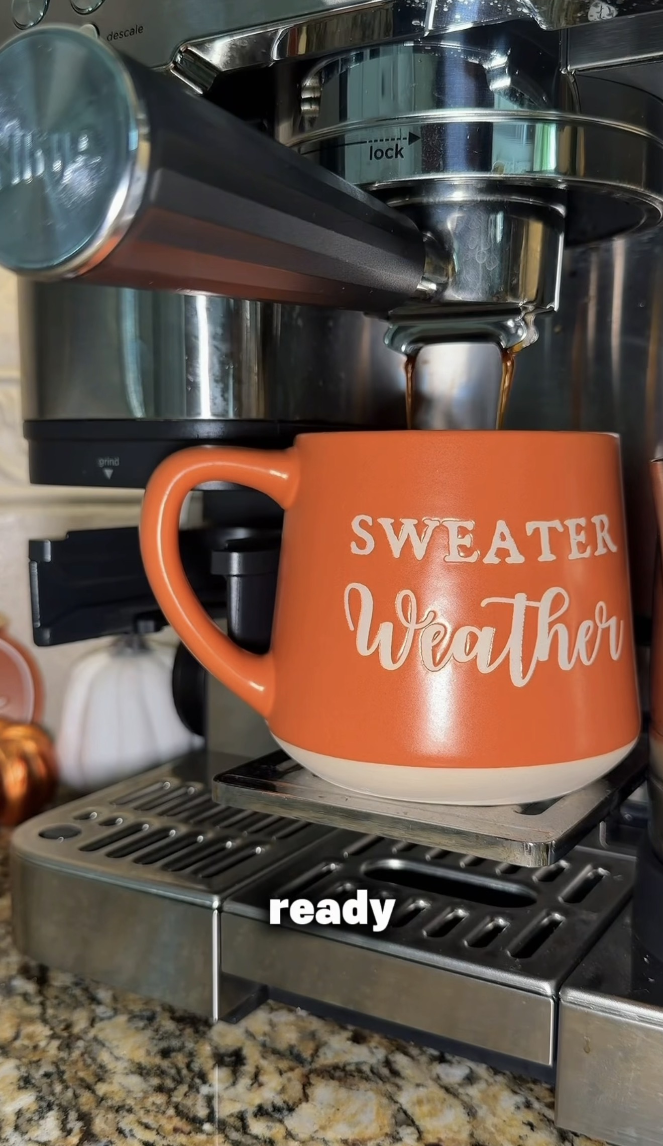 Close-up detail shot of coffee pouring into an orange mug under an espresso machine
