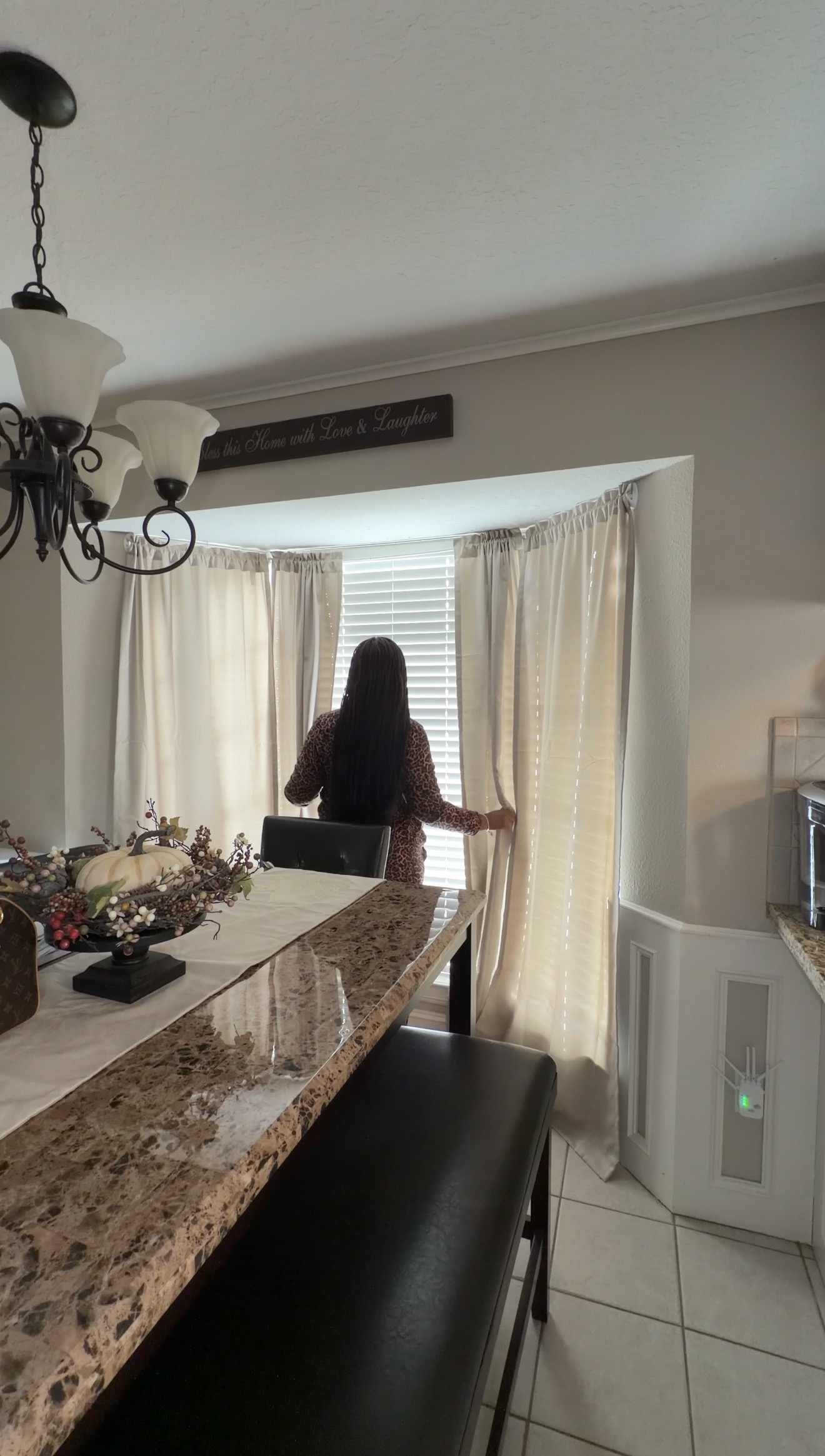Finished vertical shot of a woman opening curtains by the window in a dining area